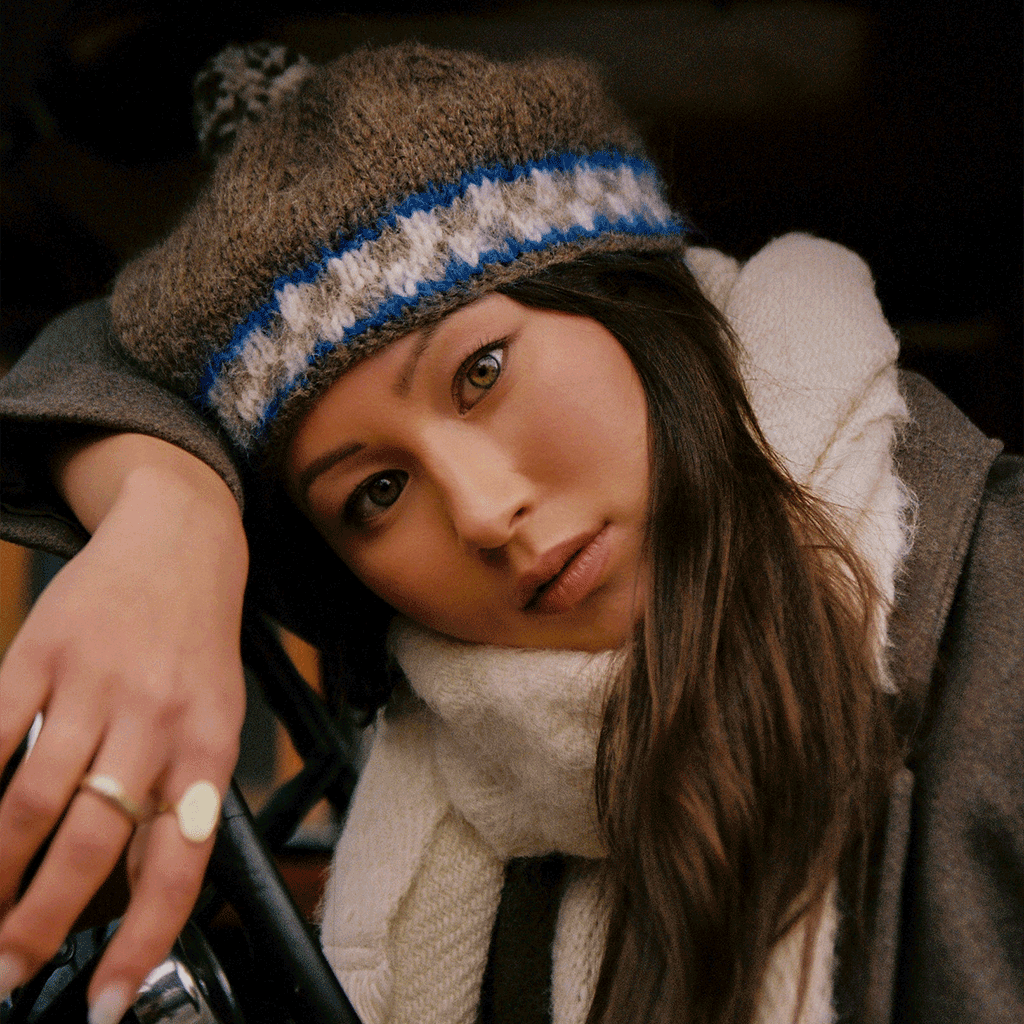 woman with head again steering wheel wearing white scarf and knit beret