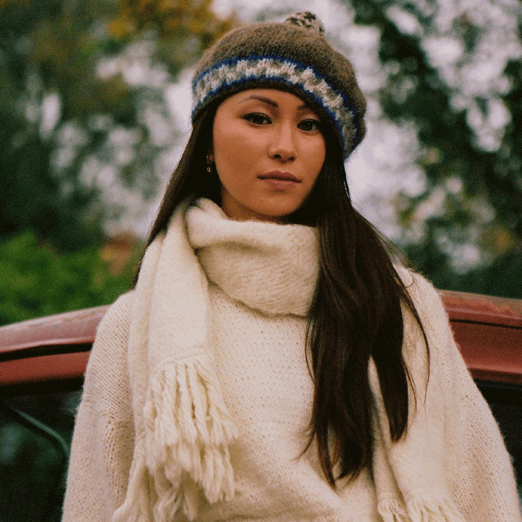 woman in white sweater, scarf and a grey beret, outside looking at camera