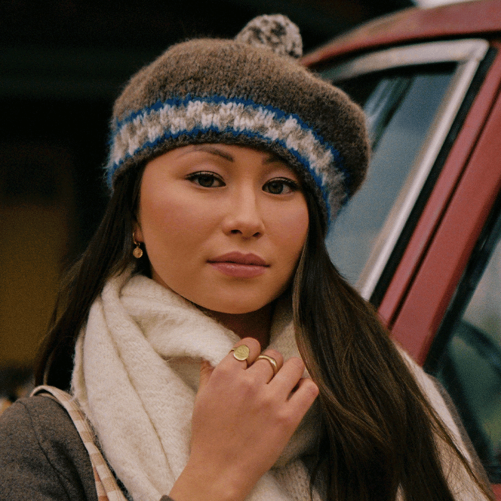 women wearing grey, blue, white beret, outside in front of red truck