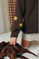 Close-up of hand-embroidered yellow flowers on the sleeve of the Buster Brown hand-knit sweater