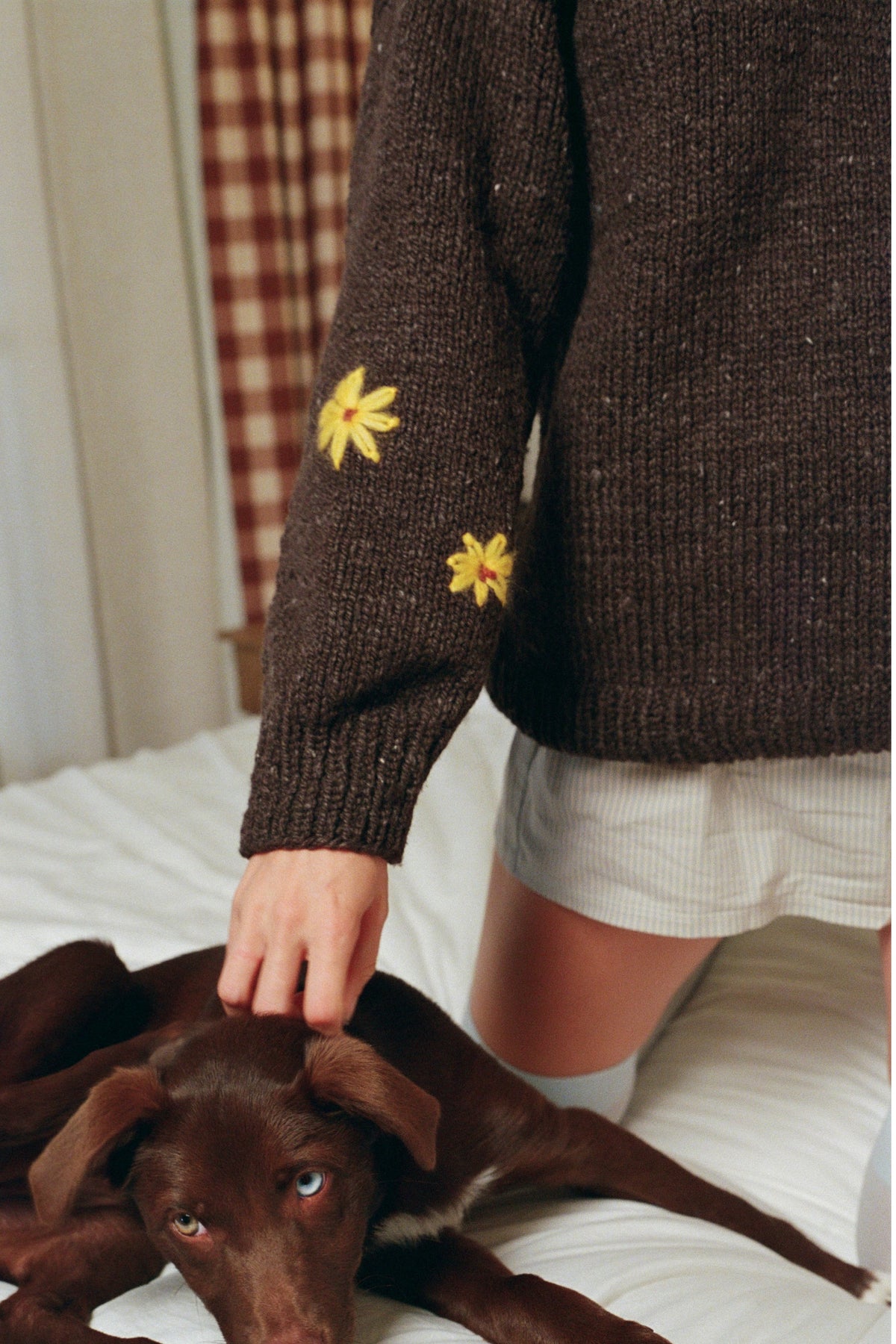 Close-up of hand-embroidered yellow flowers on the sleeve of the Buster Brown hand-knit sweater