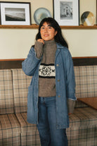 Hand knit flower sweater layered under a denim jacket, styled with jeans