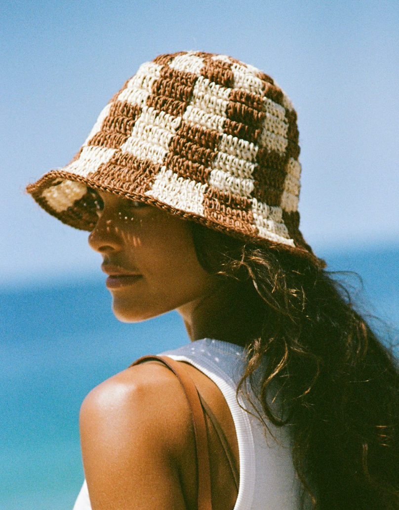 Woman wearing a checkered sun hat on a beach